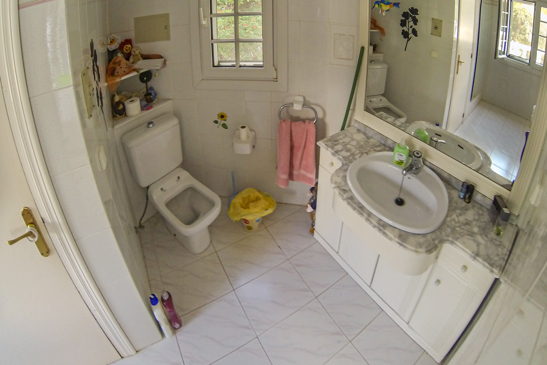 Salle de bain avec lavabo en marbre, toilette et carrelage blanc.