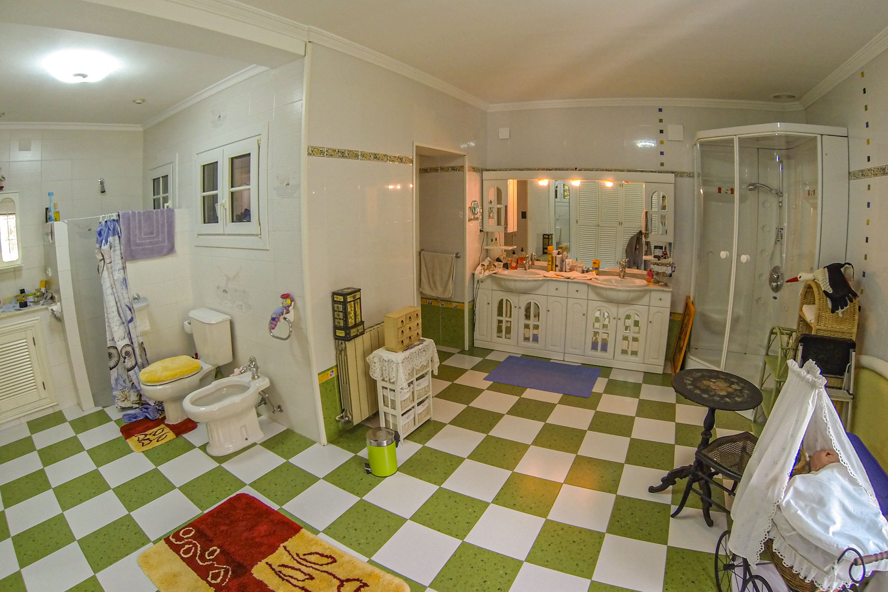 Salle de bain spacieuse avec carrelage à damier vert et blanc, double vasque et douche.