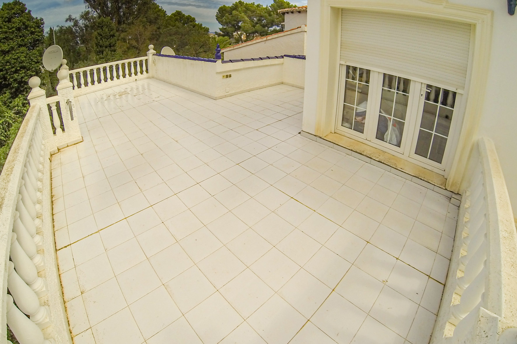 Vaste terrasse avec carrelage blanc et balustrade, idéale pour profiter du plein air.