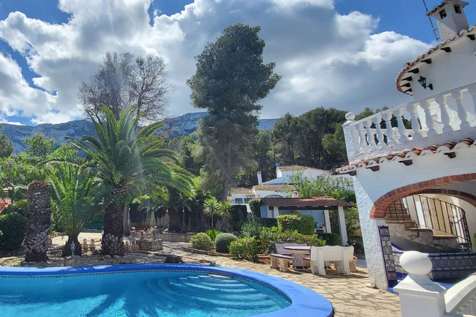 Vue de la piscine bleue avec accès progressif, entourée de jardins et de la maison principale à Denia.