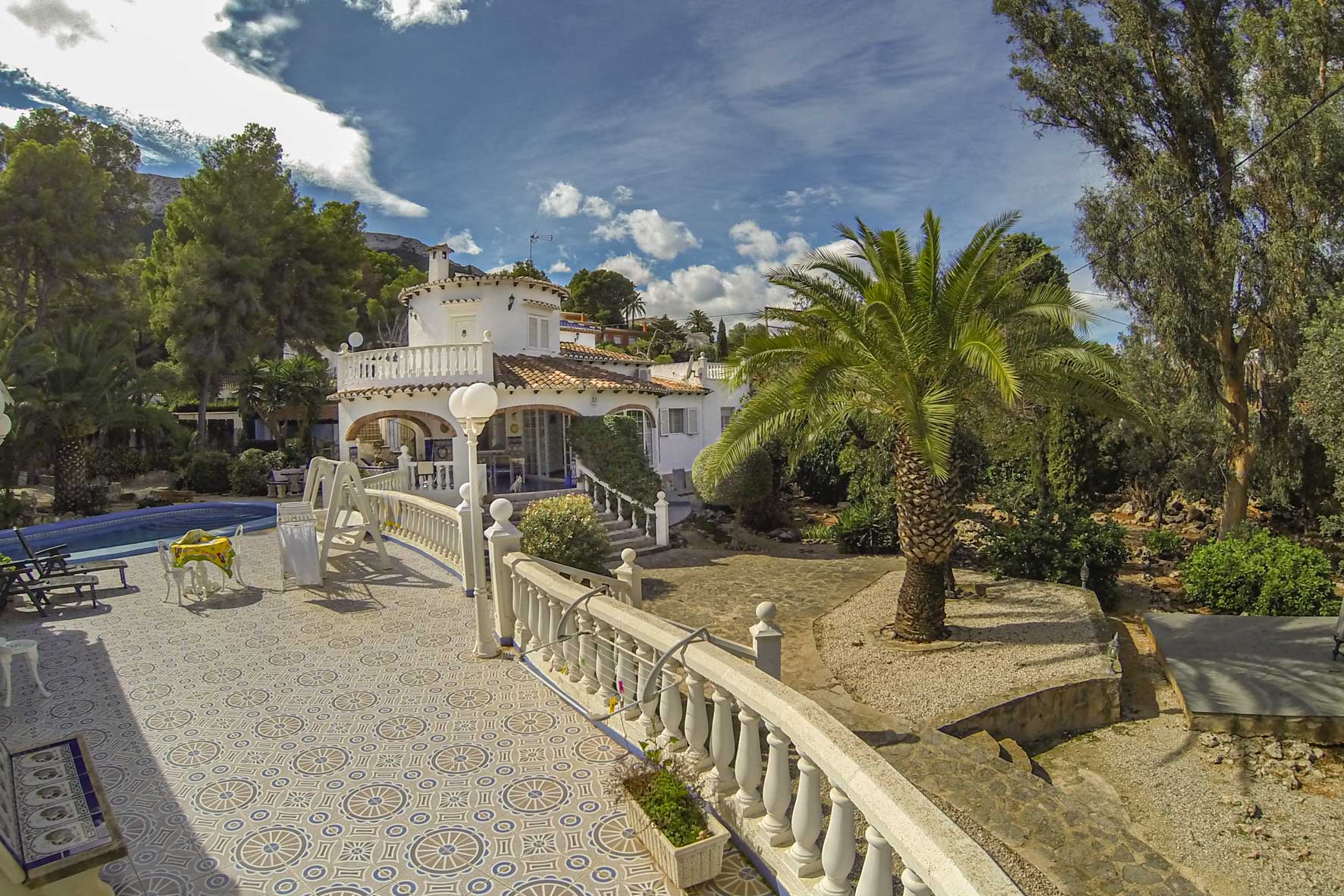 Vue de la terrasse carrelée à motifs, de la balustrade et de la piscine de la villa.