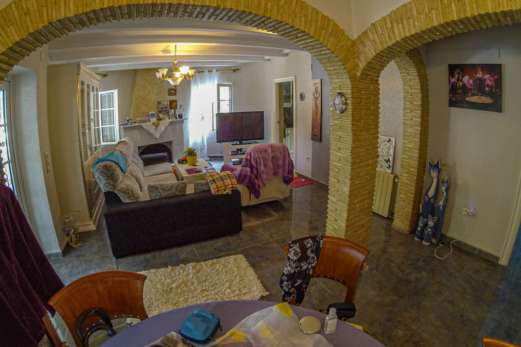 Vue du salon avec des arches en pierre, une cheminée en marbre et un mobilier éclectique.