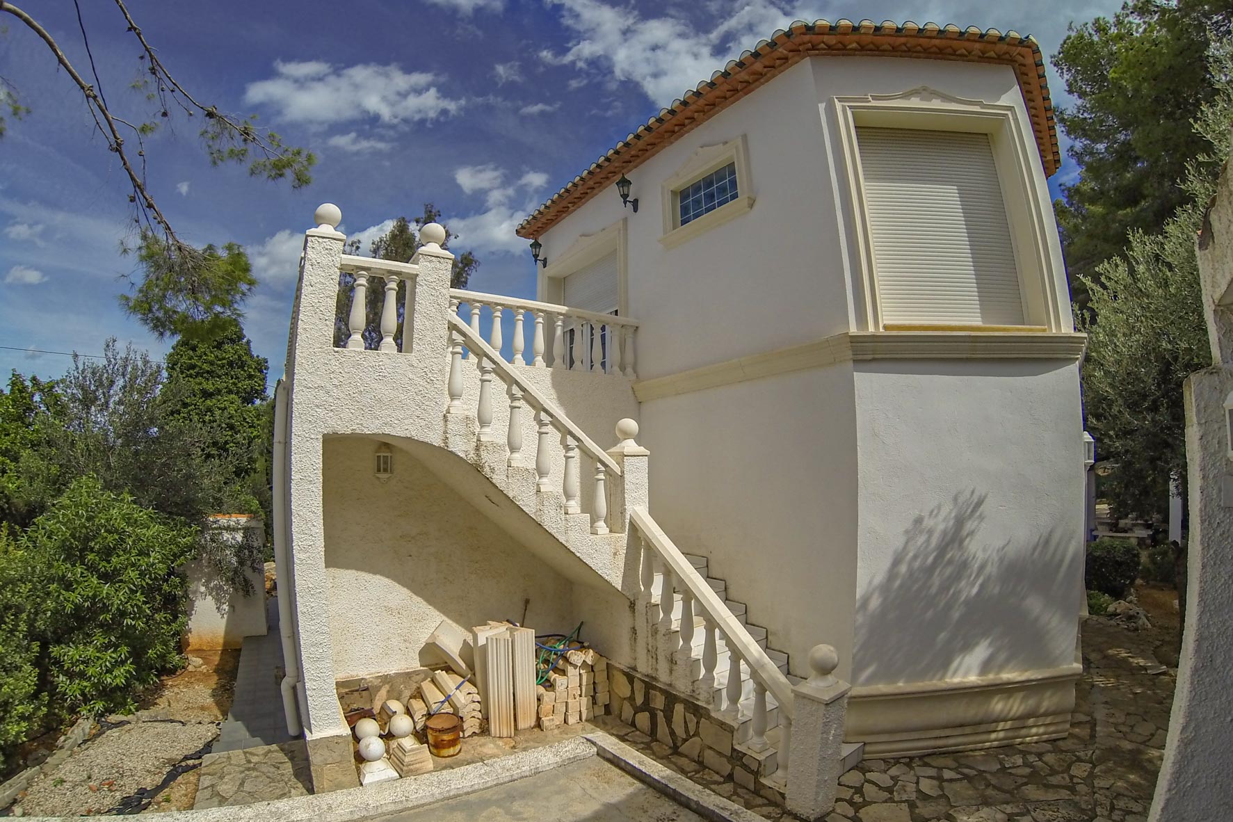 Vue extérieure de l'escalier en pierre blanche avec balustrade menant à la tour de la villa.