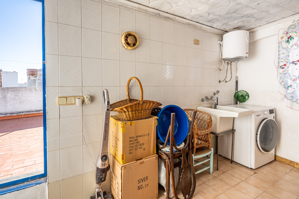 Buanderie et espace de rangement avec lave-linge, chauffe-eau électrique et accès direct à la terrasse sur le toit en terre cuite.