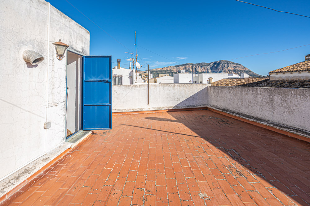 Terrasse sur le toit avec revêtement en terre cuite, offrant une vue dégagée sur le massif du Montgó et les toits environnants du village.