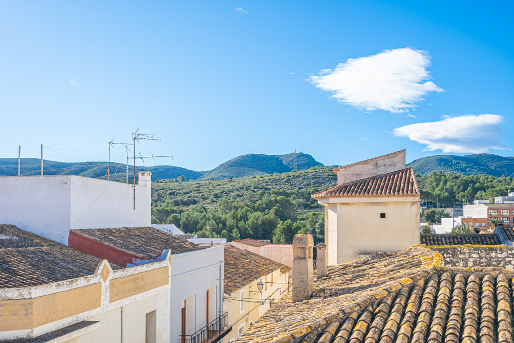 Vue panoramique depuis la terrasse sur le toit, surplombant les toits de tuiles traditionnels et les montagnes de la réserve naturelle.