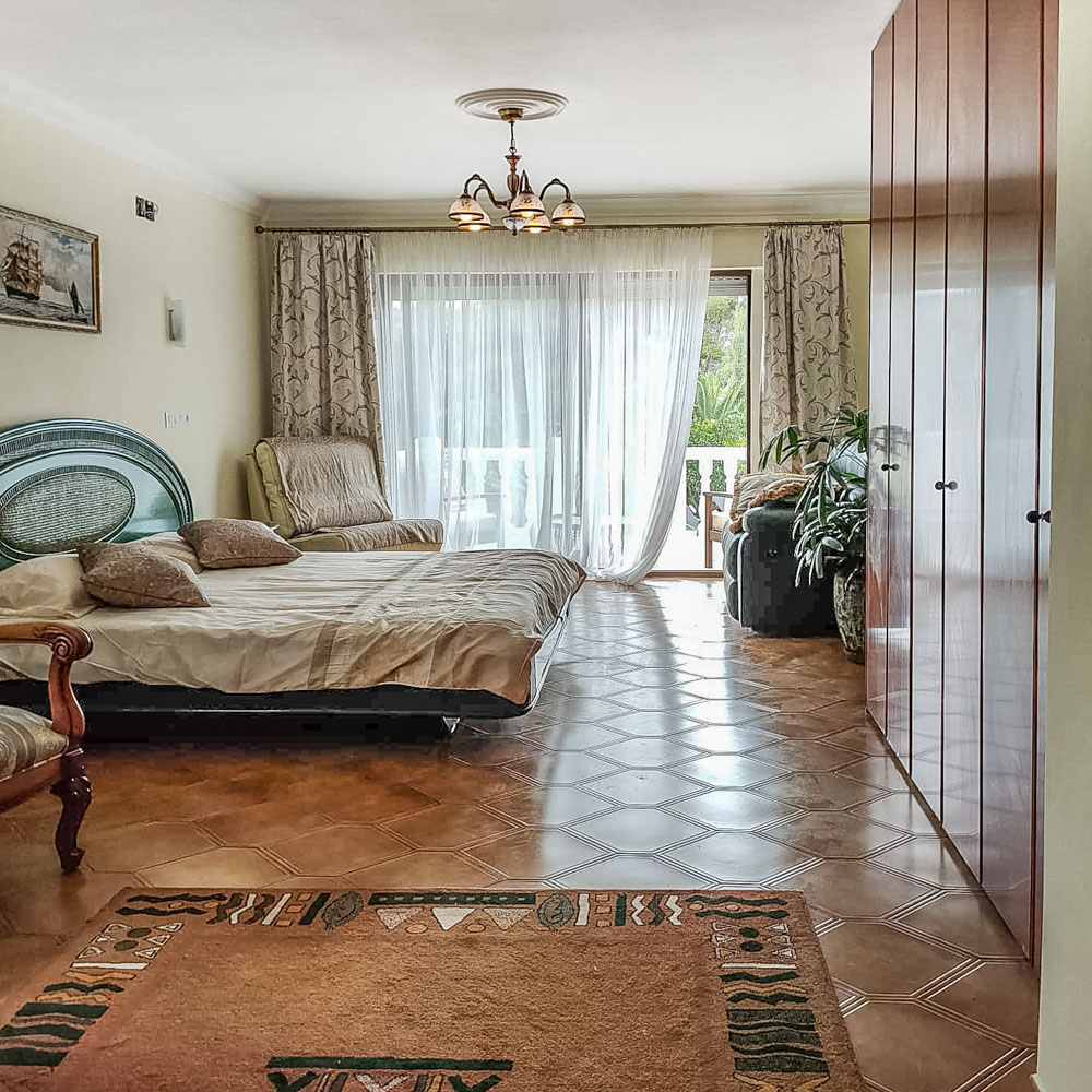 Chambre spacieuse avec placards intégrés en bois, sol en carrelage décoratif et accès direct à une terrasse privée par de grandes baies vitrées.