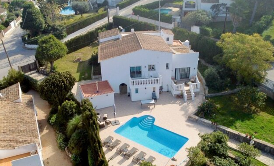 Vue aérienne de la villa illustrant la piscine privée, la grande terrasse ensoleillée et le jardin méditerranéen entourant la façade blanche classique.