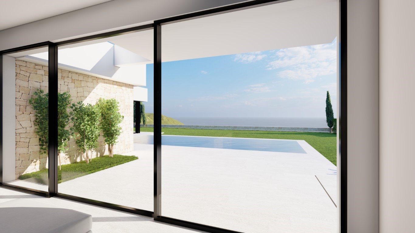 Vue depuis l'intérieur à travers de larges baies vitrées sur la terrasse en pierre blanche, la piscine et la mer à l'horizon.