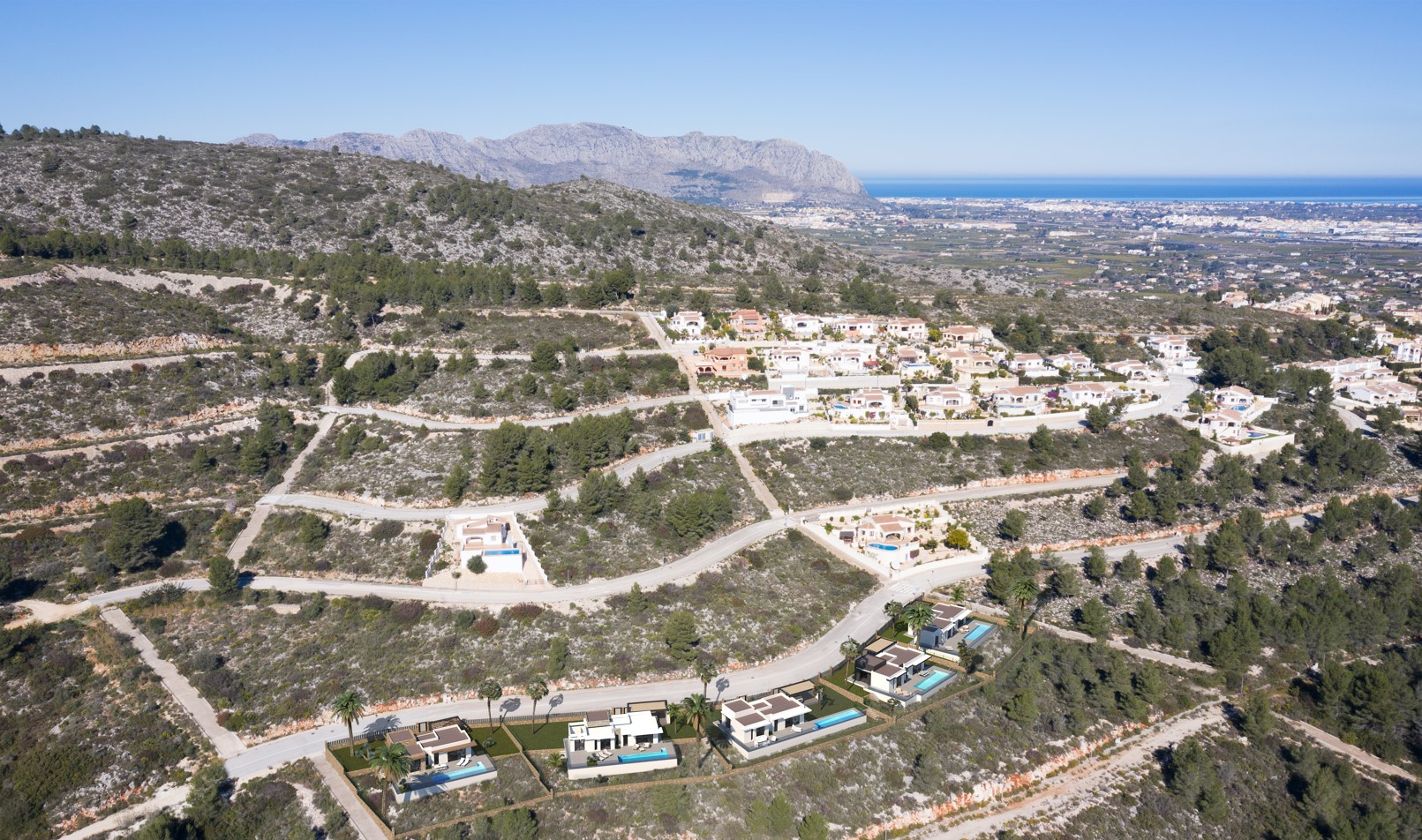 Vue aérienne du lotissement à Pedreguer, illustrant l'emplacement des villas modernes avec piscine et les vues dégagées sur la mer et les montagnes environnantes.