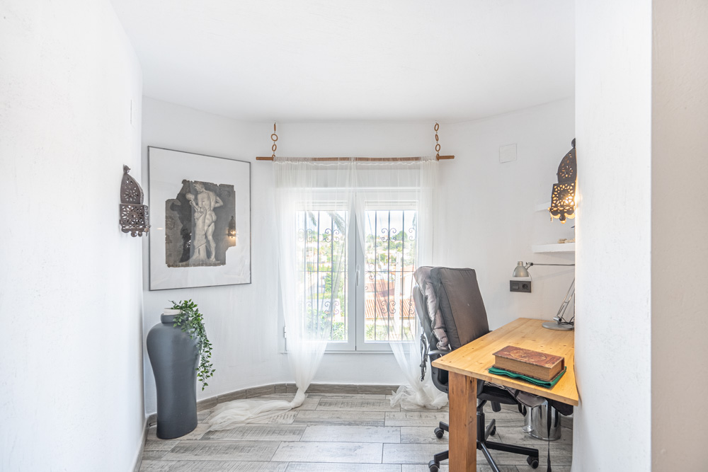 Espace bureau lumineux avec un bureau en bois, un sol en céramique imitation bois et une fenêtre sécurisée laissant entrer la lumière naturelle.