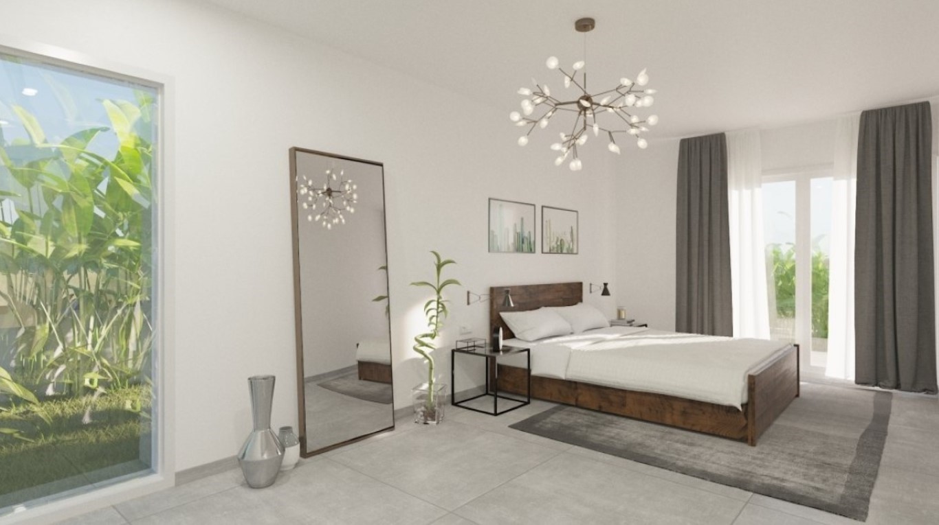 Chambre principale avec cadre de lit en bois sombre, lustre moderne en forme de branche et grandes fenêtres offrant une vue sur la végétation.