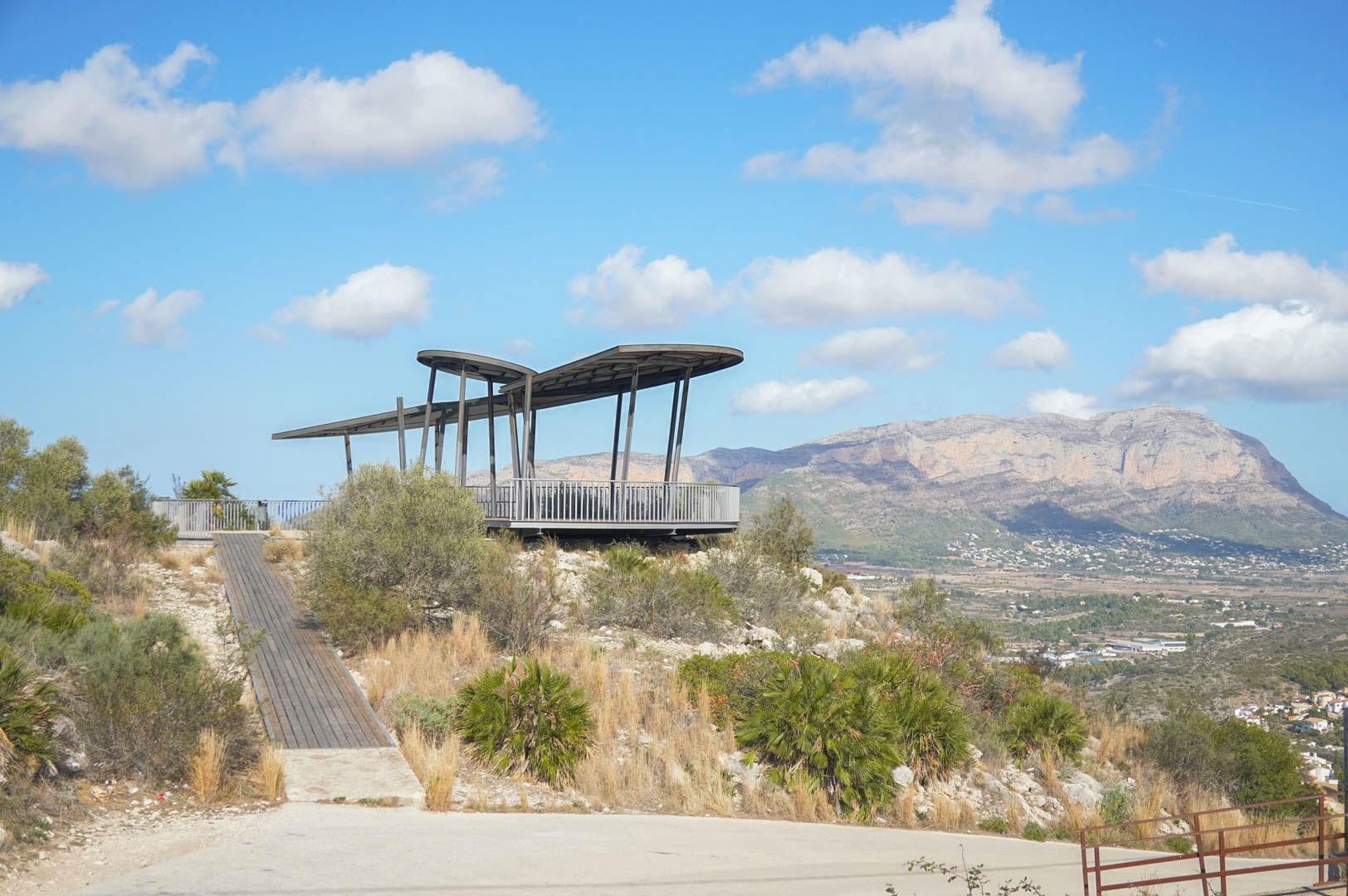 Belvédère architectural moderne avec passerelle en bois, offrant une vue panoramique sur la vallée et le massif du Montgó à La Sella.