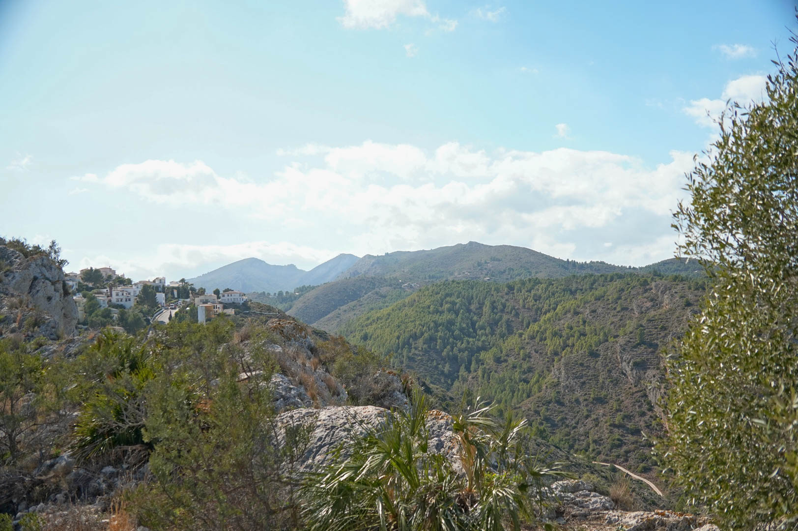 Vue panoramique de La Sella avec maisons blanches et montagnes boisées.