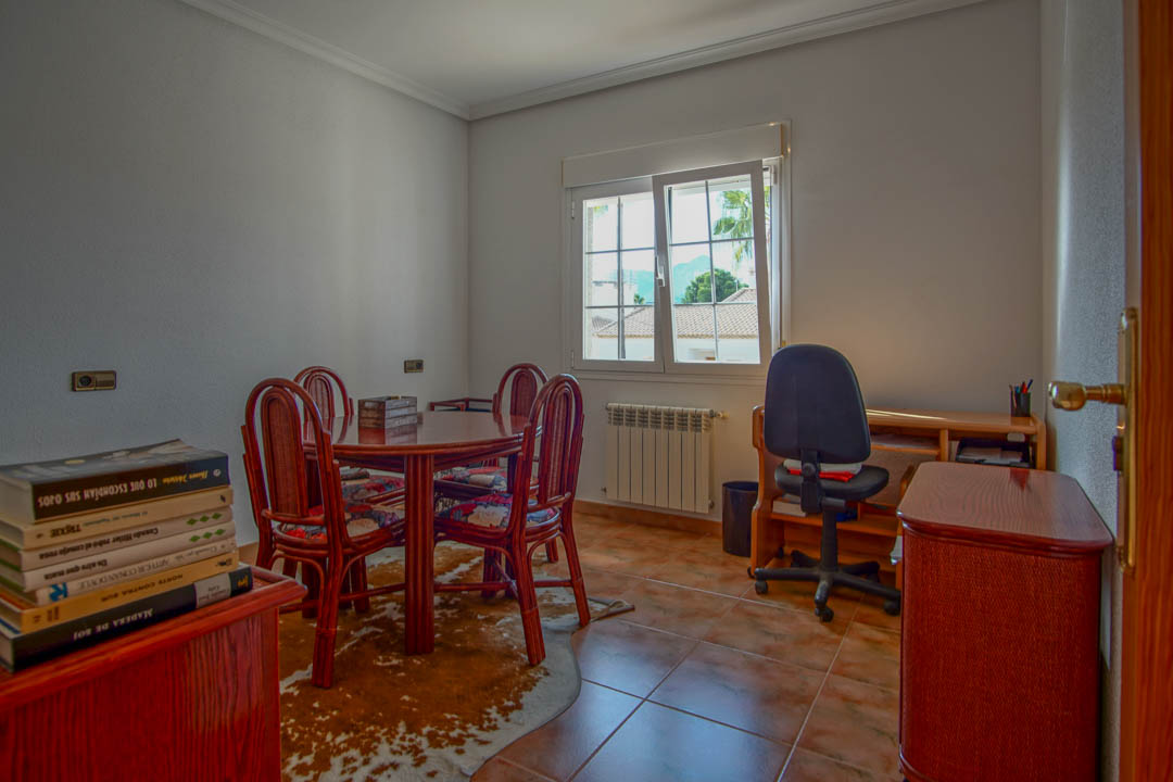 Bureau lumineux avec sol en grès, table en bois massif et coin travail. La fenêtre apporte une belle lumière naturelle et une vue sur le quartier résidentiel.