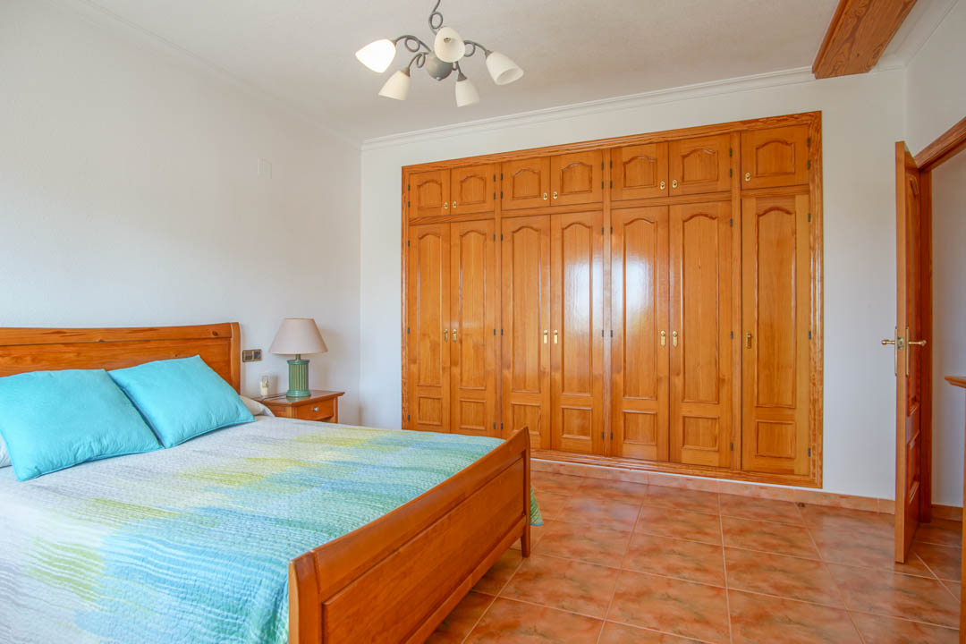 Chambre à coucher avec une grande armoire encastrée en bois massif sur mesure, sol en grès cérame et mobilier en bois assorti.