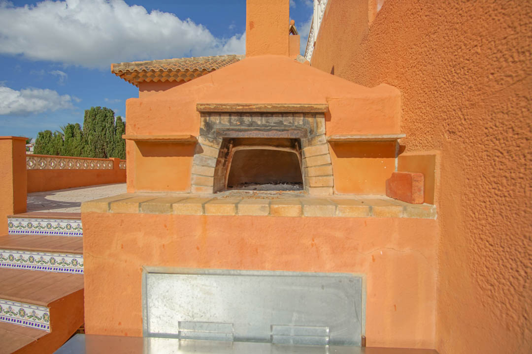 Four à bois traditionnel intégré sur la terrasse extérieure, doté d'une arche en briques et d'un escalier orné de carreaux de faïence décoratifs.