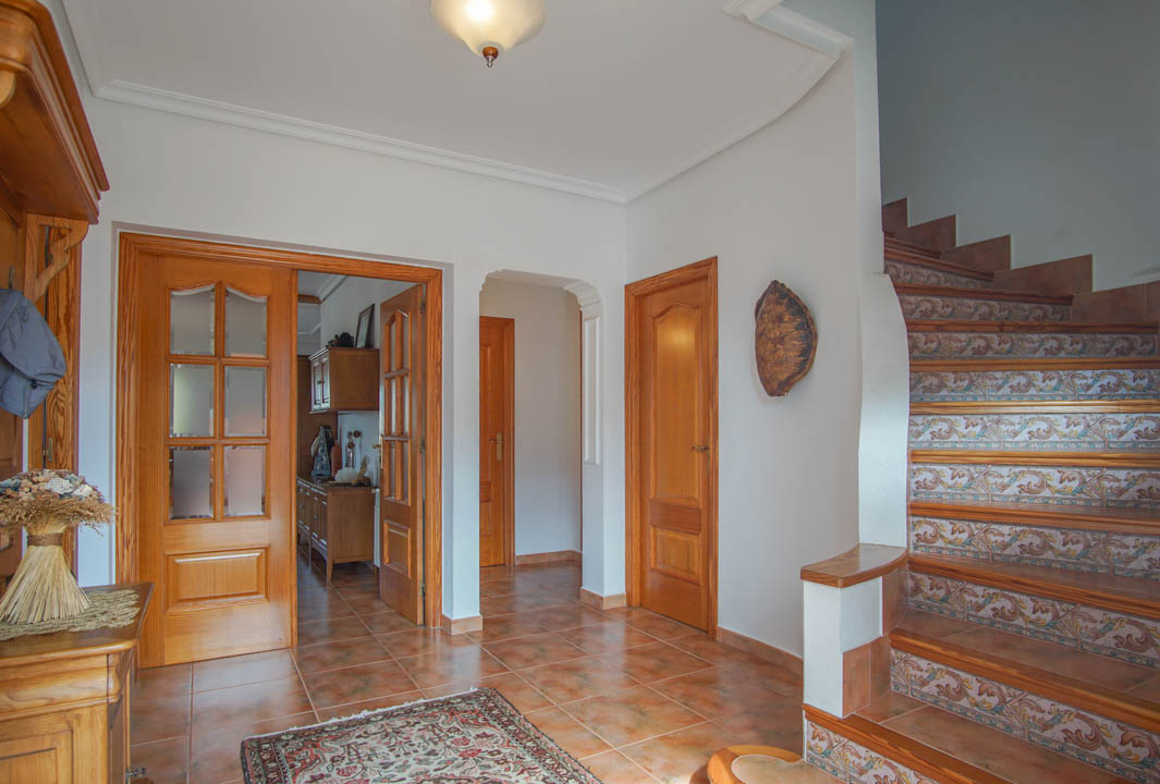 Hall d'entrée avec sol en grès cérame, portes en bois massif et escalier orné de contremarches en céramique traditionnelle méditerranéenne.