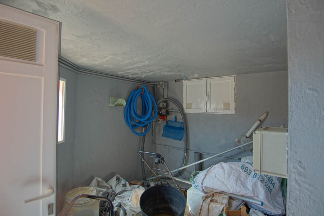Local technique et espace de rangement avec murs gris, comprenant l'équipement d'entretien de la piscine et les installations de service de la villa.