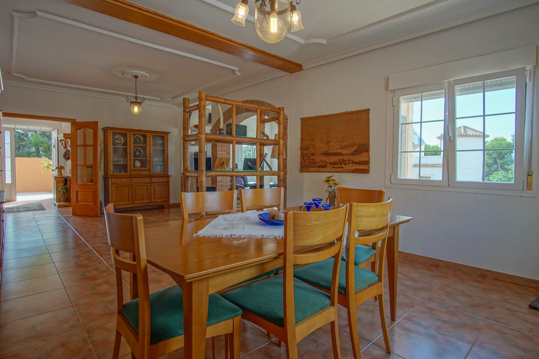 Salle à manger avec table en bois massif, sol en grès cérame et moulures au plafond. Un séparateur en bambou et une arche en briques complètent cet espace lumineux.