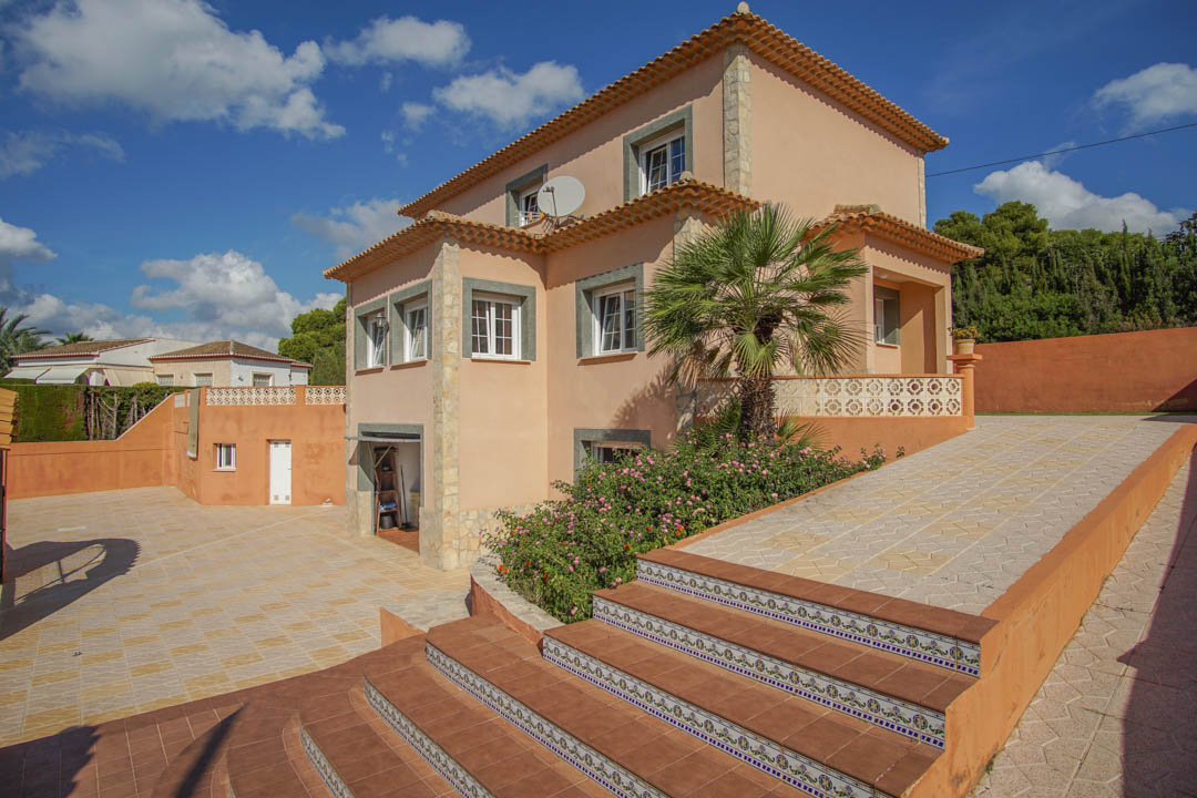 Vue extérieure de la villa sur trois niveaux avec façade ocre, escaliers ornés de carreaux traditionnels et une grande cour pavée.