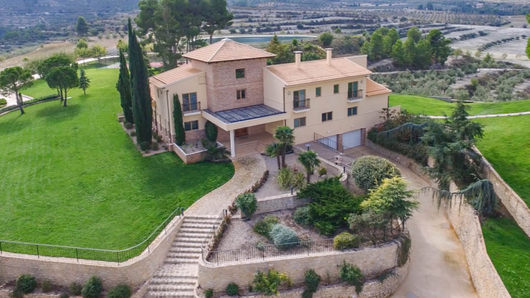 Vue aérienne de la villa principale alliant pierre et enduit, avec ses jardins paysagers, ses murs en pierre naturelle et un panorama sur les vallées environnantes.
