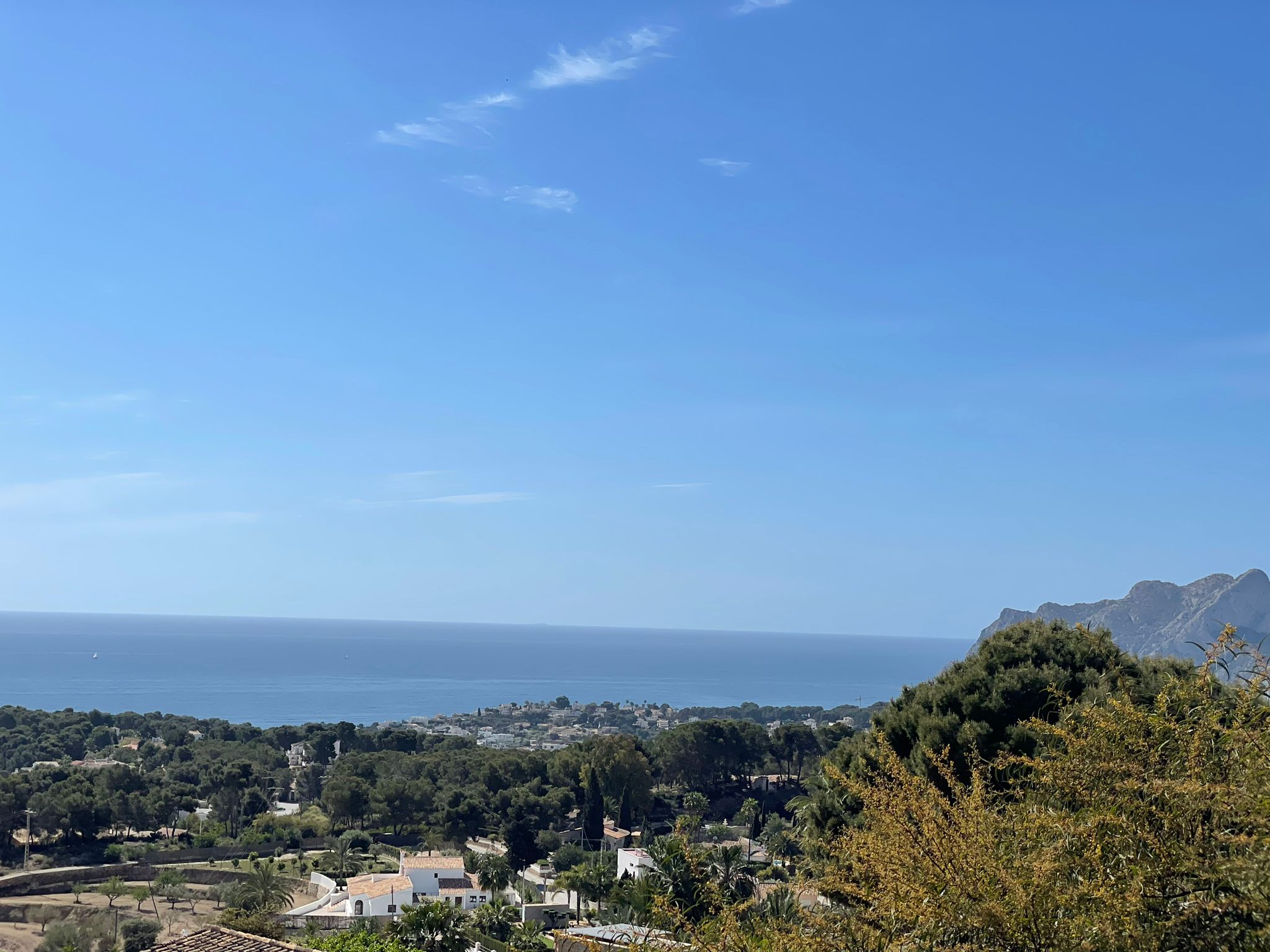 Vue panoramique sur le littoral méditerranéen avec des forêts de pins et des villas résidentielles sous un ciel dégagé.