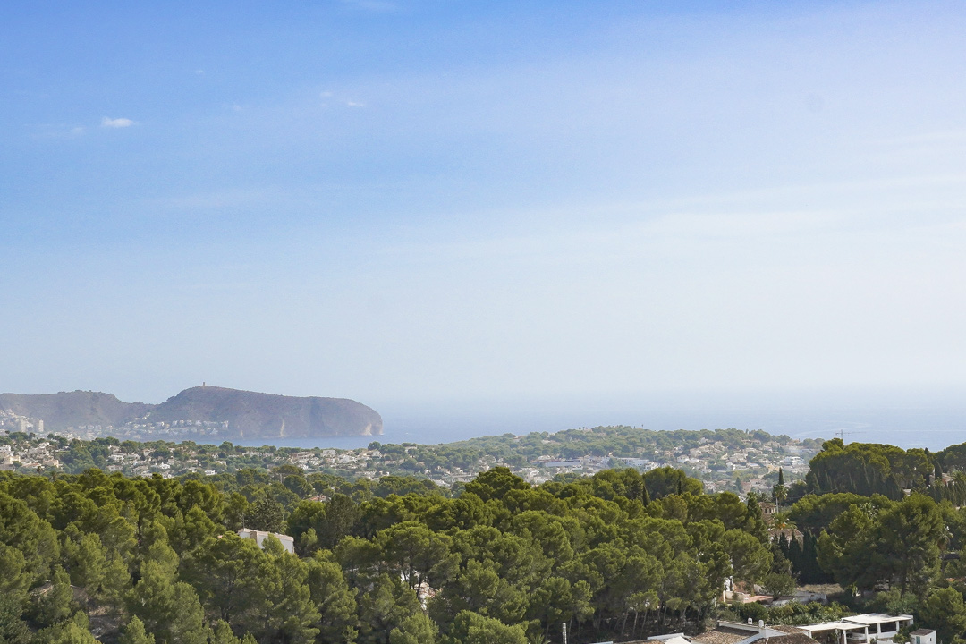 Vues panoramiques sur la côte de Benissa, mettant en évidence le Cap D'or à Moraira surplombant une vaste forêt de pins et la mer Méditerranée.