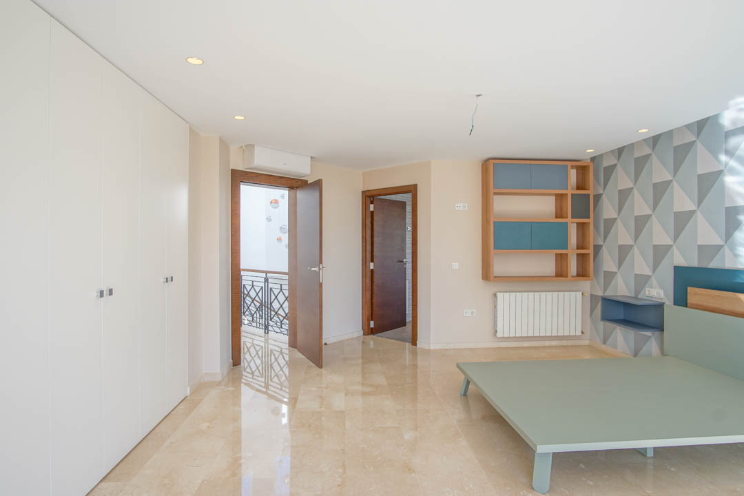 Chambre avec sol en marbre poli, grands placards intégrés blancs et mur à motifs géométriques. Comprend une étagère murale en bois et un accès direct au palier.