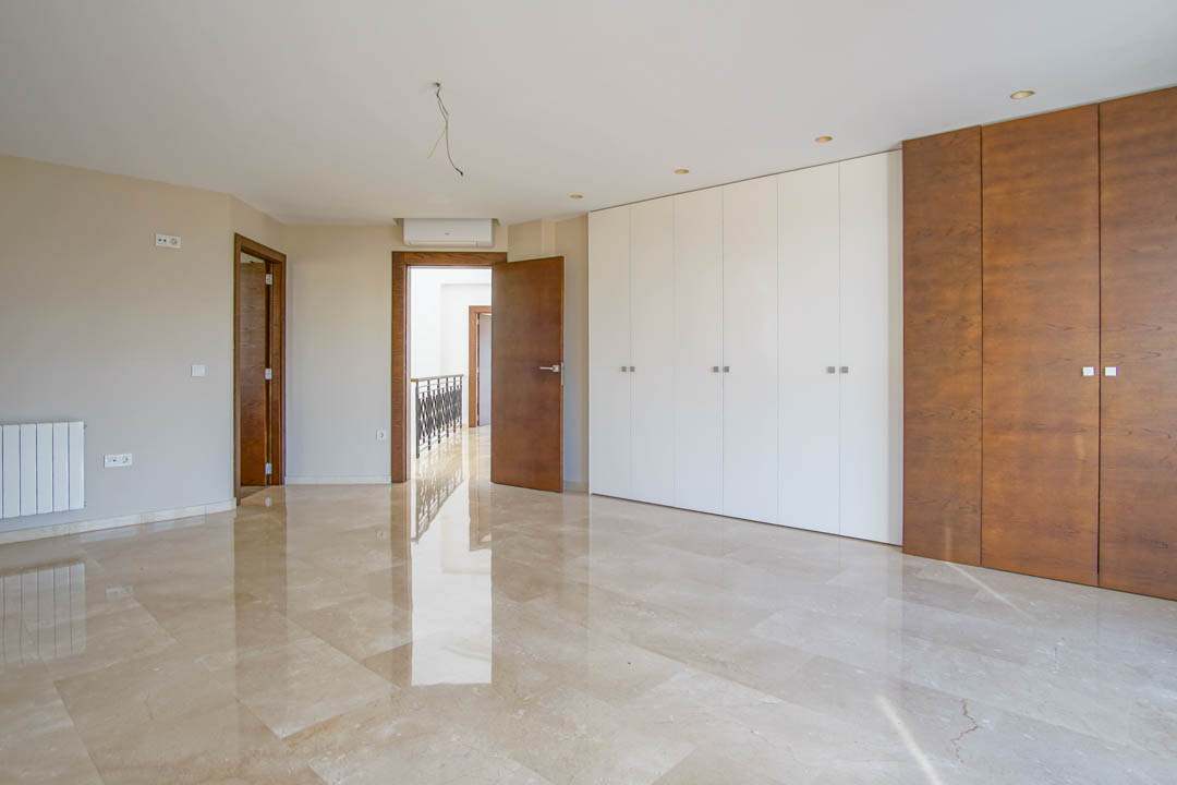 Chambre spacieuse avec sol en marbre poli, grands placards intégrés bicolores et climatisation. La pièce bénéficie d'une lumière naturelle abondante et de finitions en bois.