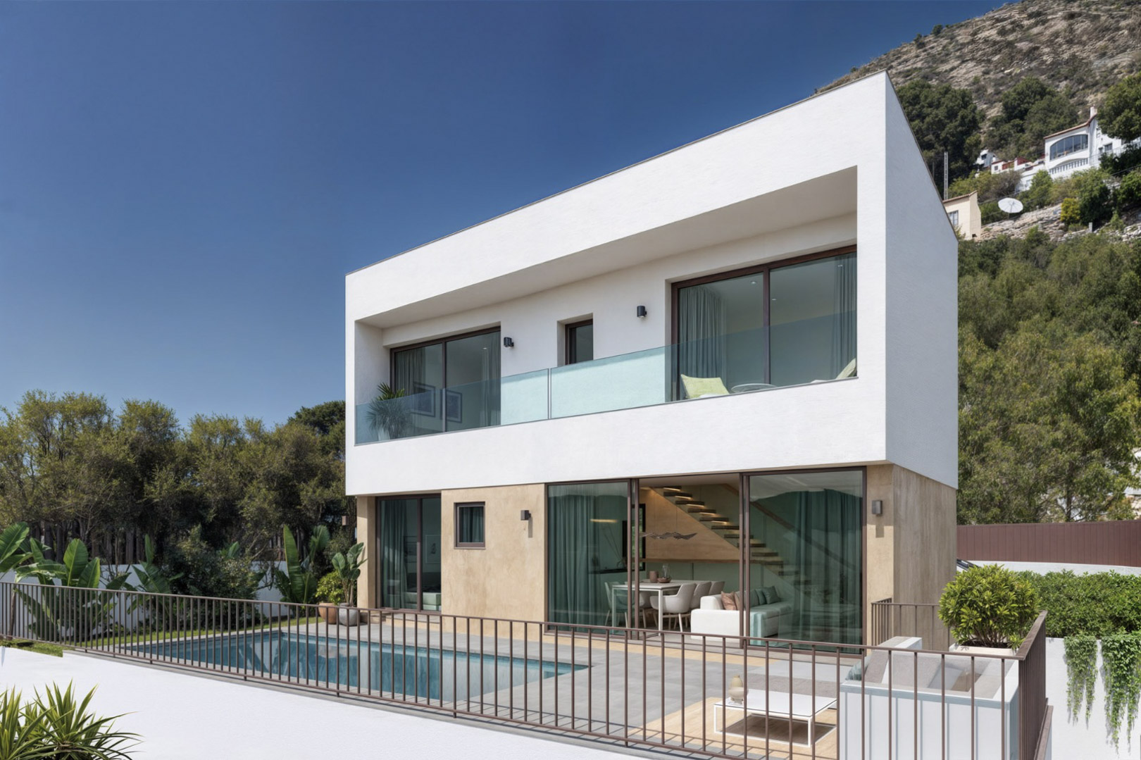 Villa moderne sur deux niveaux avec piscine privée, terrasse en grès et baies vitrées révélant un intérieur lumineux avec un escalier en bois suspendu.