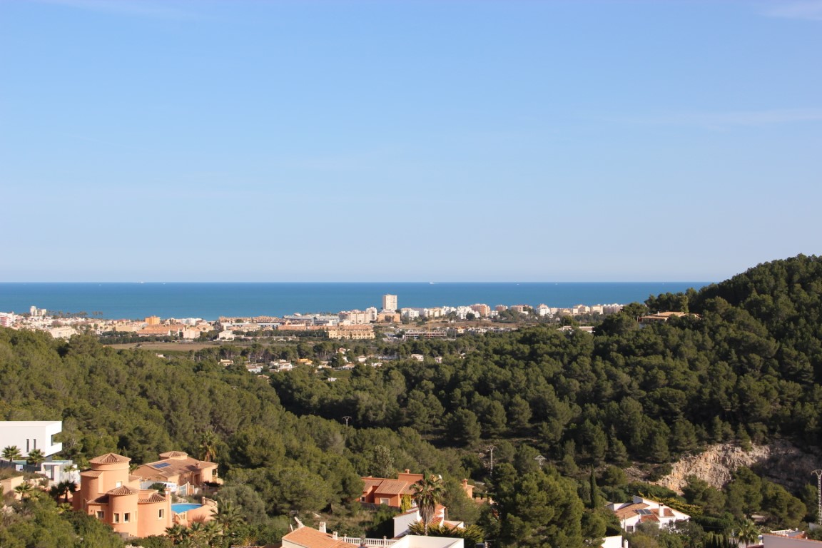 Vues panoramiques sur la mer Méditerranée et le littoral de Jávea depuis les parcelles en hauteur, entourées d'une forêt de pins dense.
