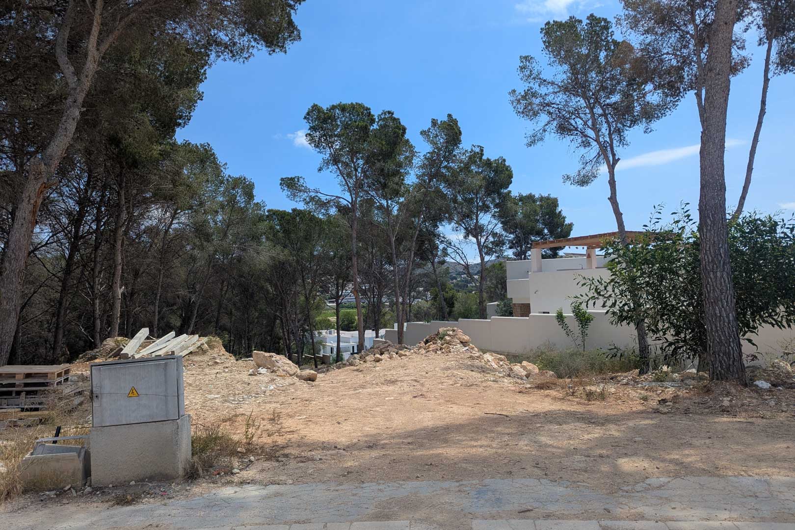 Terrain à bâtir surélevé entouré de pins matures, offrant une surface préparée pour le début immédiat des travaux de construction.
