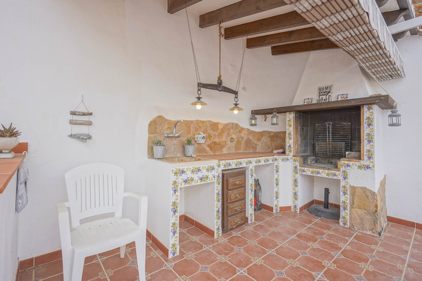 Barbecue extérieur avec comptoir en pierre et carreaux décoratifs dans une villa de style espagnol.