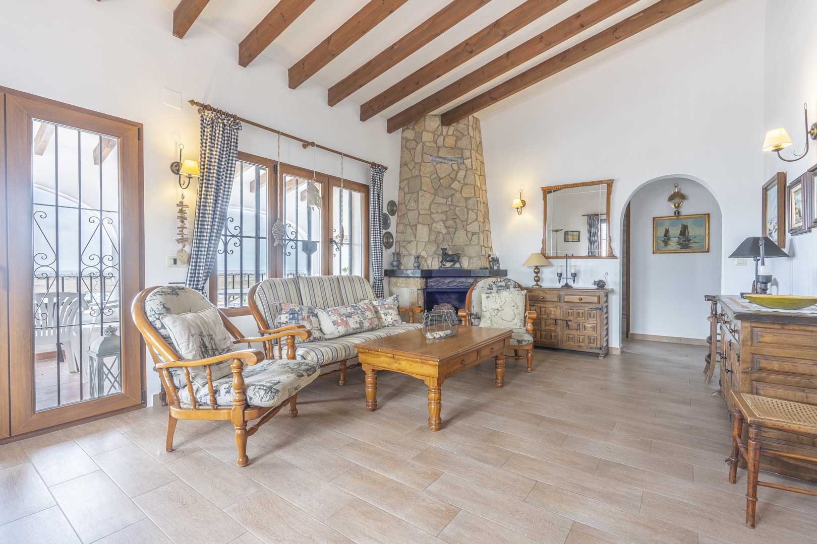 Salon avec cheminée en pierre, poutres apparentes et mobilier de style rustique.
