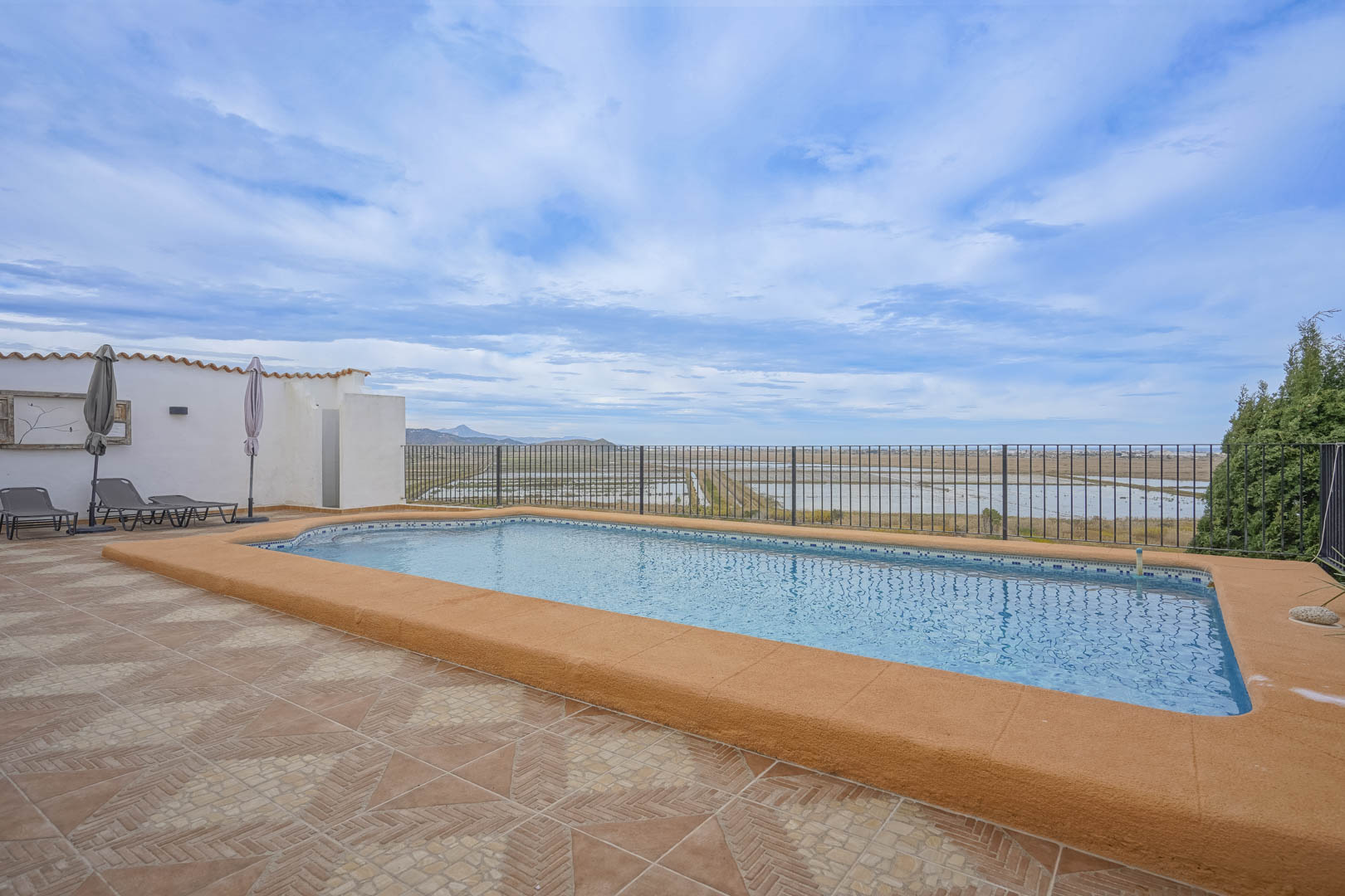 Vue de la piscine avec bordure ocre et carrelage en terre cuite, donnant sur la réserve naturelle.