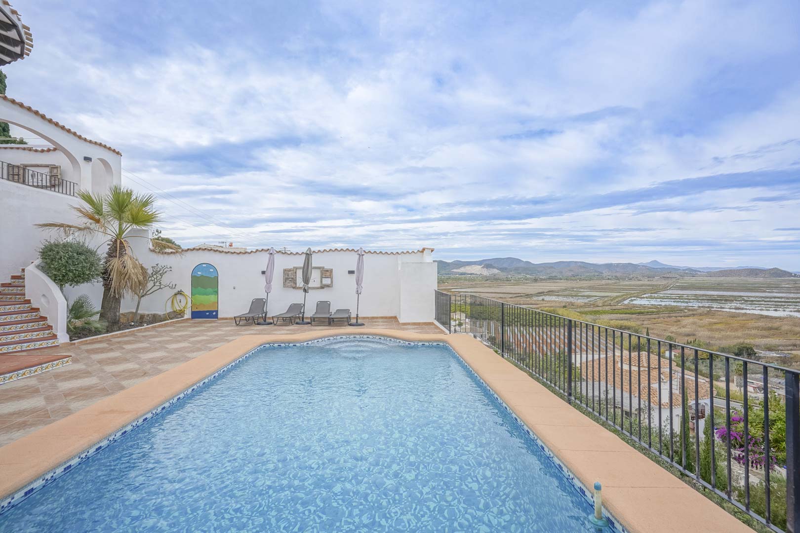 Vue sur la piscine privée carrelée de bleu et terrasse avec vue panoramique sur la réserve naturelle.
