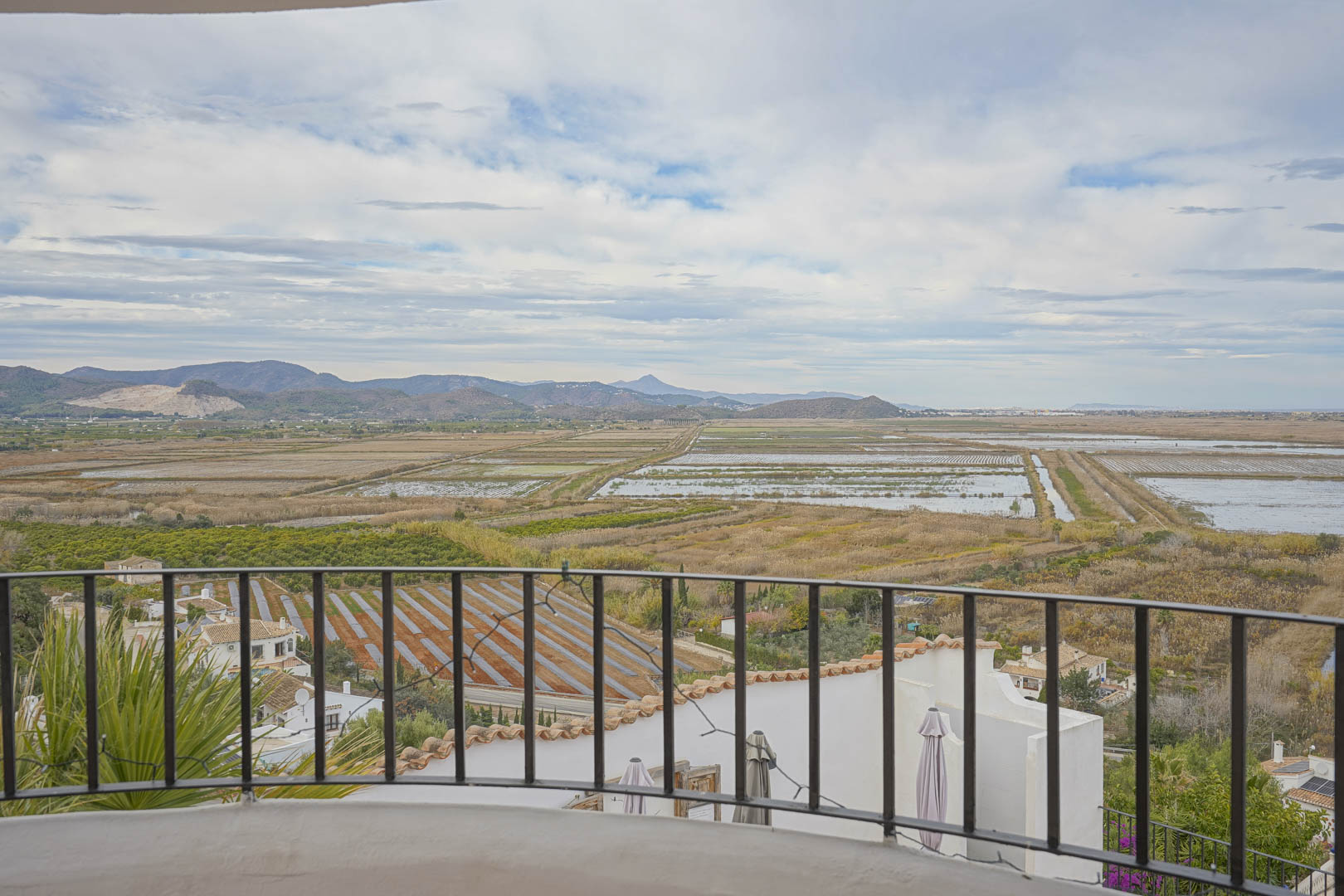 Vues panoramiques depuis la terrasse avec rambarde en fer forgé sur les rizières et le paysage montagneux.