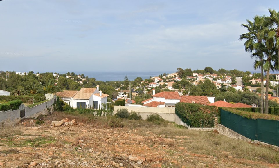 Vue surélevée de l'urbanisation avec des maisons aux toits rouges et vue sur la mer.