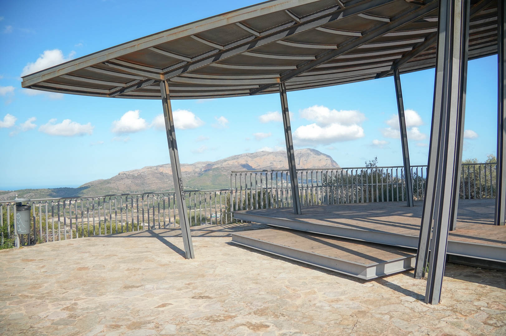 Belvédère extérieur avec structure métallique moderne et terrasse en bois, offrant des vues panoramiques sur les montagnes et la vallée environnante.