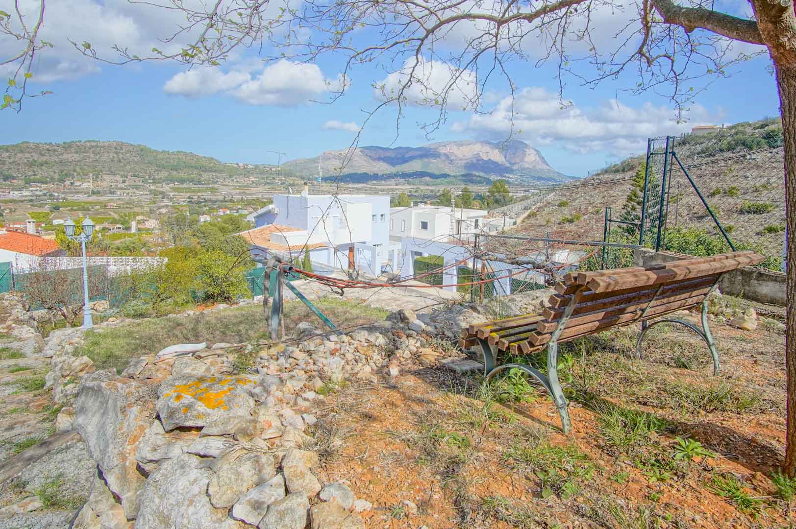 Belvédère privé avec banc en bois et muret en pierre naturelle, offrant une vue panoramique sur la vallée et les montagnes environnantes sous un ciel dégagé.