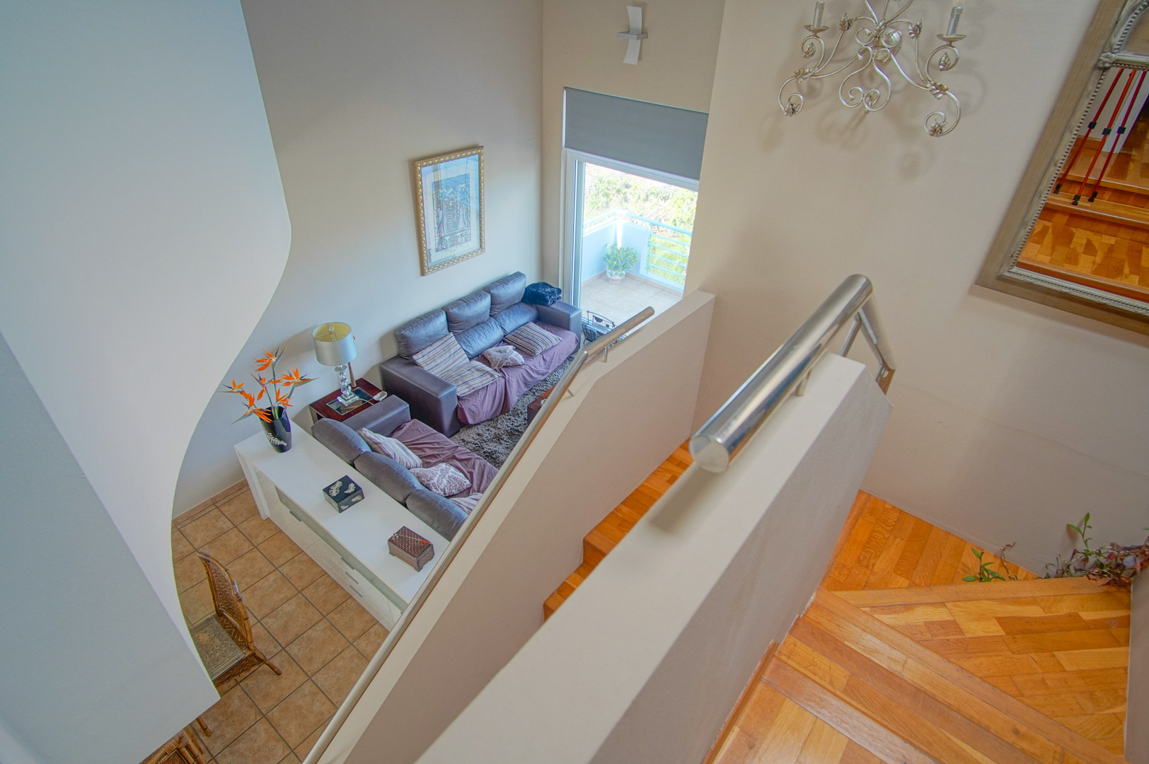 Vue depuis l'étage supérieur sur l'escalier en bois et le salon à double hauteur, mettant en valeur les volumes spacieux et l'accès à la terrasse.
