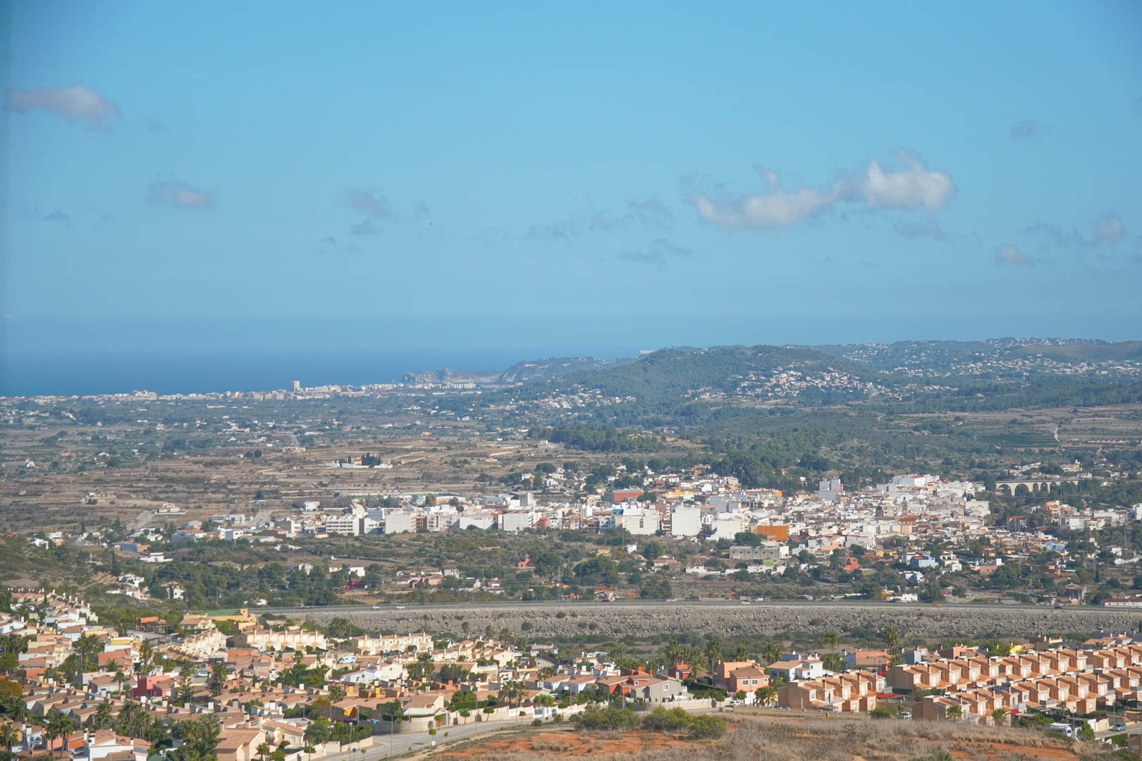 Vue panoramique depuis la propriété sur la vallée de Pedreguer et le littoral méditerranéen sous un ciel bleu dégagé.