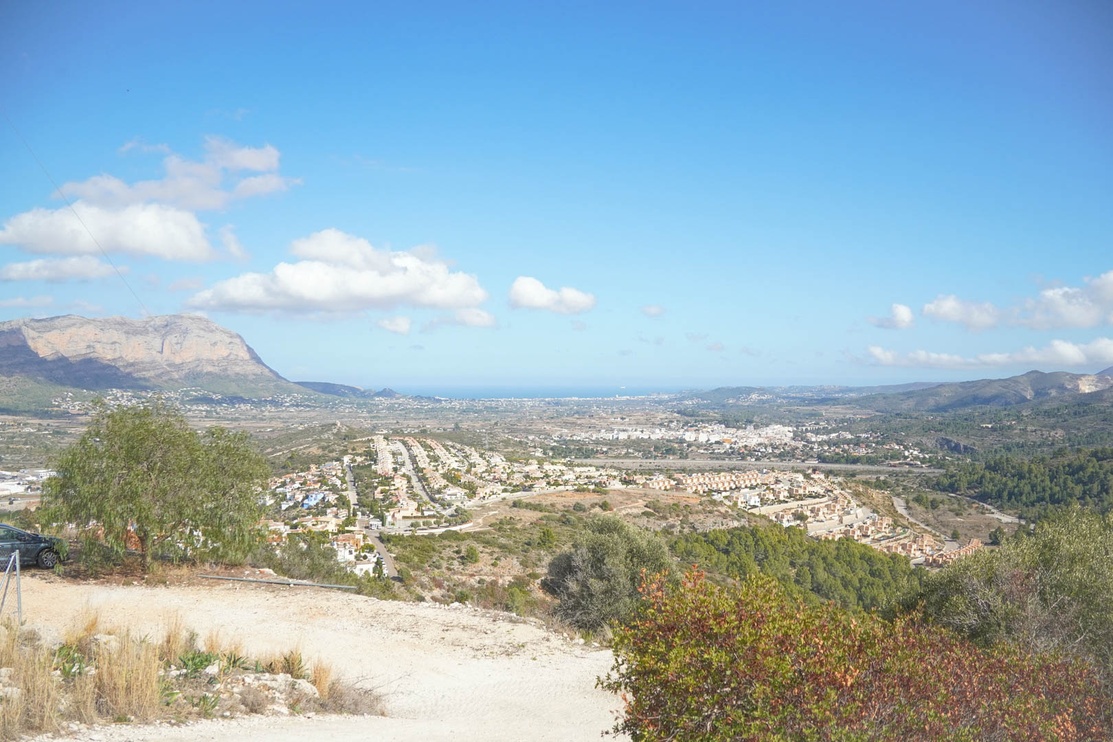 Vue panoramique surélevée sur la vallée de Pedreguer, incluant le massif du Montgó et la mer Méditerranée à l'horizon sous un ciel clair.