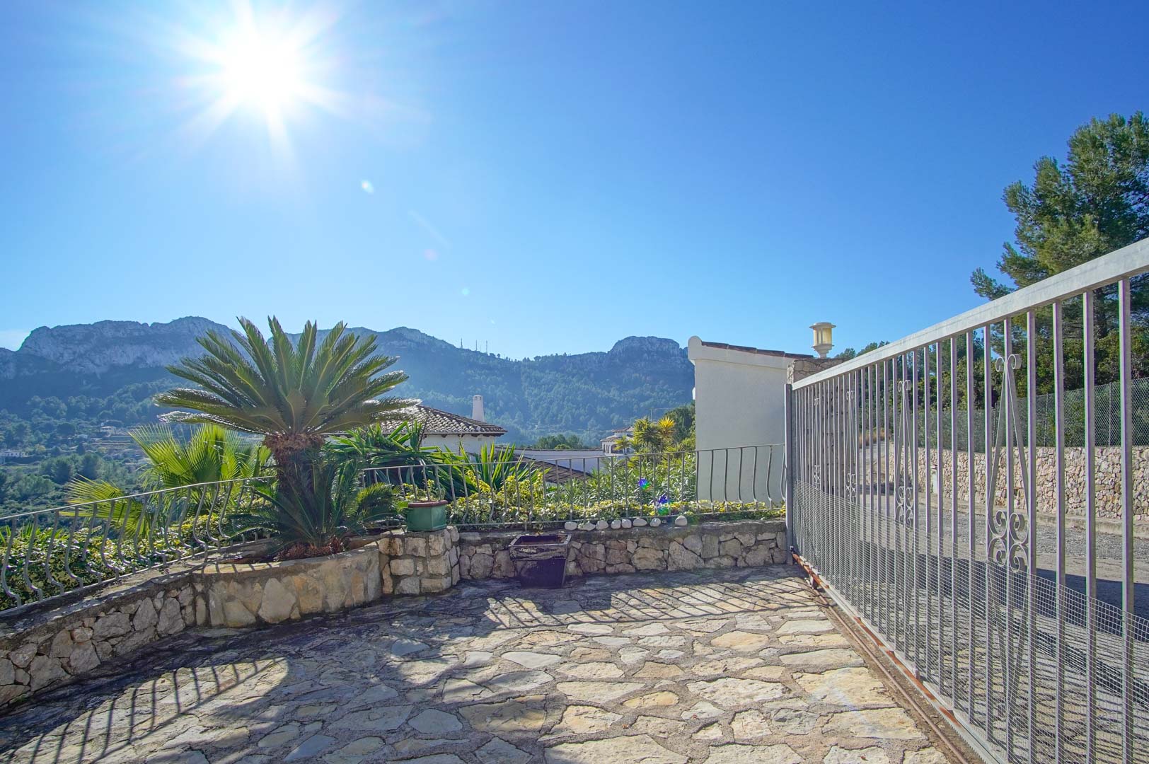Entrée de la propriété avec un sol en pierre naturelle, un portail coulissant et une vue dégagée sur les montagnes environnantes de Monte Pego.