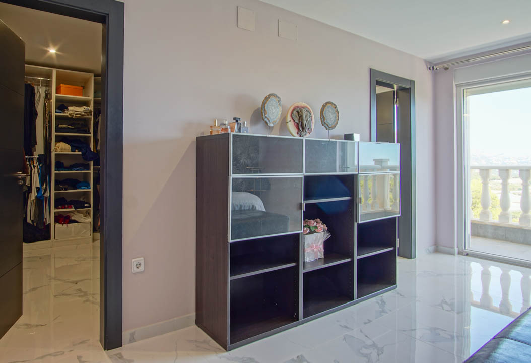 Chambre avec sols en marbre blanc, dressing attenant et accès direct à une terrasse privée bordée d'une balustrade classique.