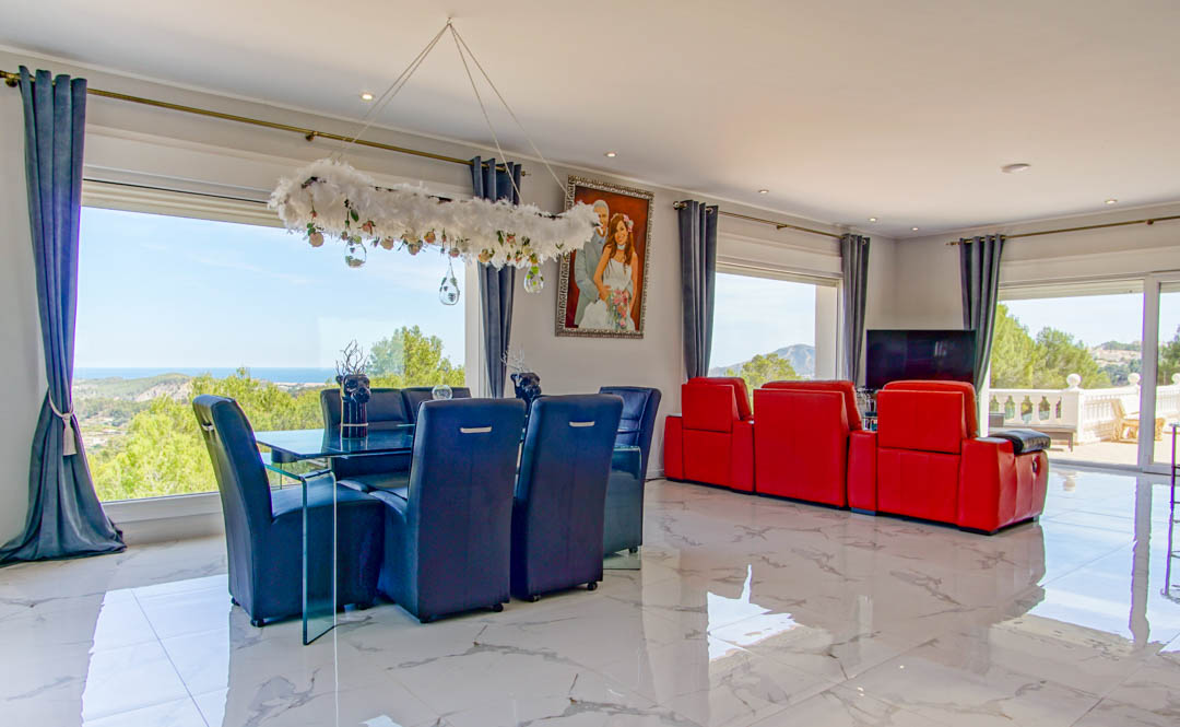 Espace de vie ouvert avec sol en marbre poli, mobilier contemporain et grandes fenêtres offrant une vue panoramique sur la mer Méditerranée et le littoral.