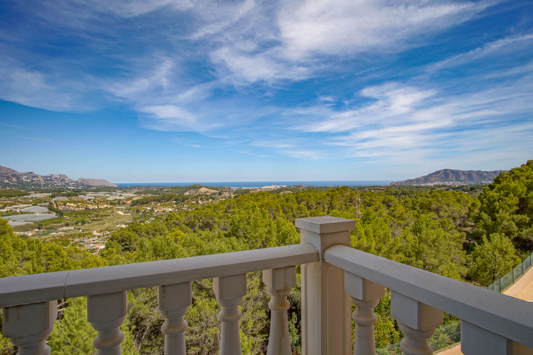 Vue panoramique depuis la terrasse avec balustrade classique, surplombant la mer Méditerranée et les forêts de pins environnantes de La Nucía.