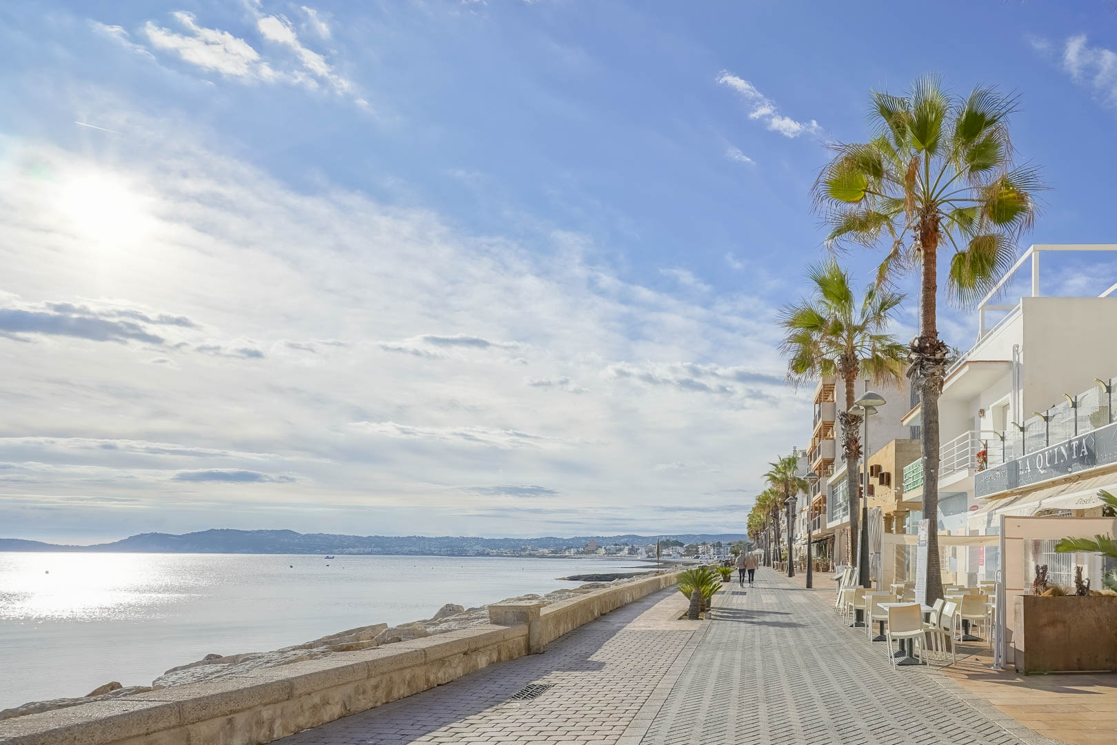 Promenade côtière de Jávea avec vue sur la mer Méditerranée, bordée de palmiers et de bâtiments blancs, à proximité de la villa.