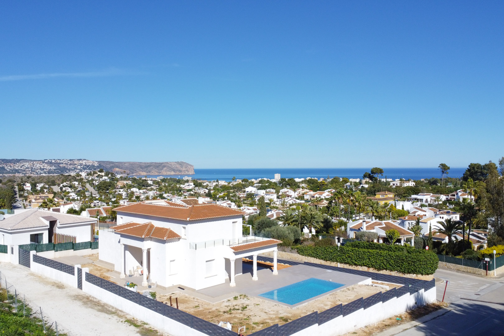 Vue aérienne de la villa à Pinosol avec toit en tuiles, piscine rectangulaire et vue panoramique sur la mer Méditerranée et la côte de Jávea.